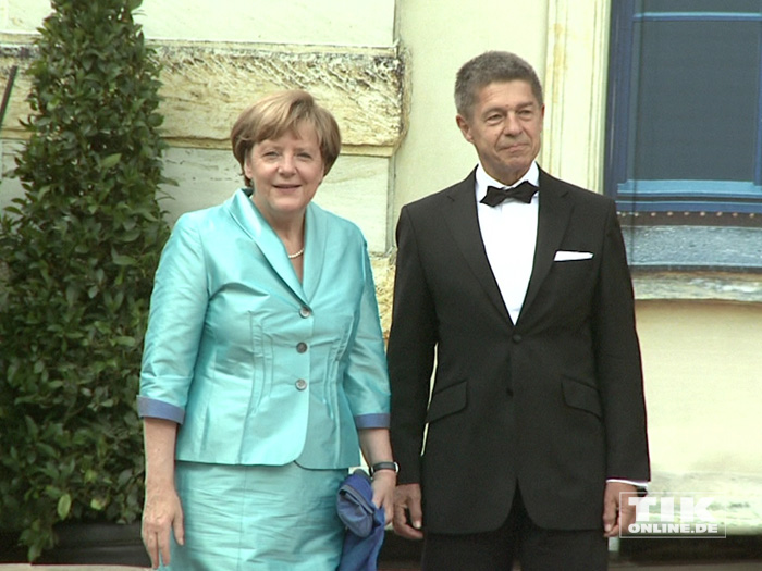 Kanzlerin Angela Merkel posiert in einem türkisen Kostüm neben ihrem Ehemann Joachim Sauer bei den Bayreuther Festspielen 2015 für die Fotografen