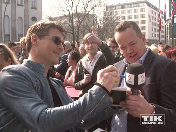 Ein Reporter bekommt von Morten Harket ein Autogramm auf sein Mikrofon