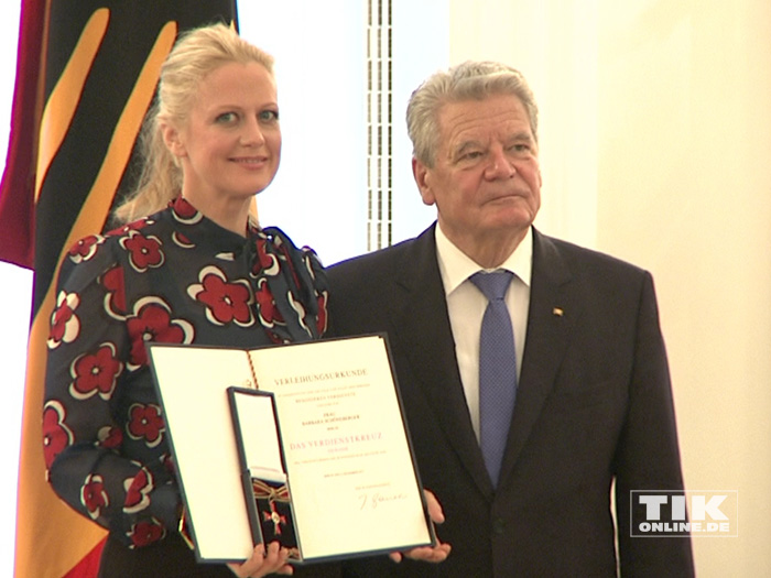 Barbara Schöneberger strahlt glücklich mit ihrem Bundesverdienstkreuz neben Bundespräsident Joachim Gauck